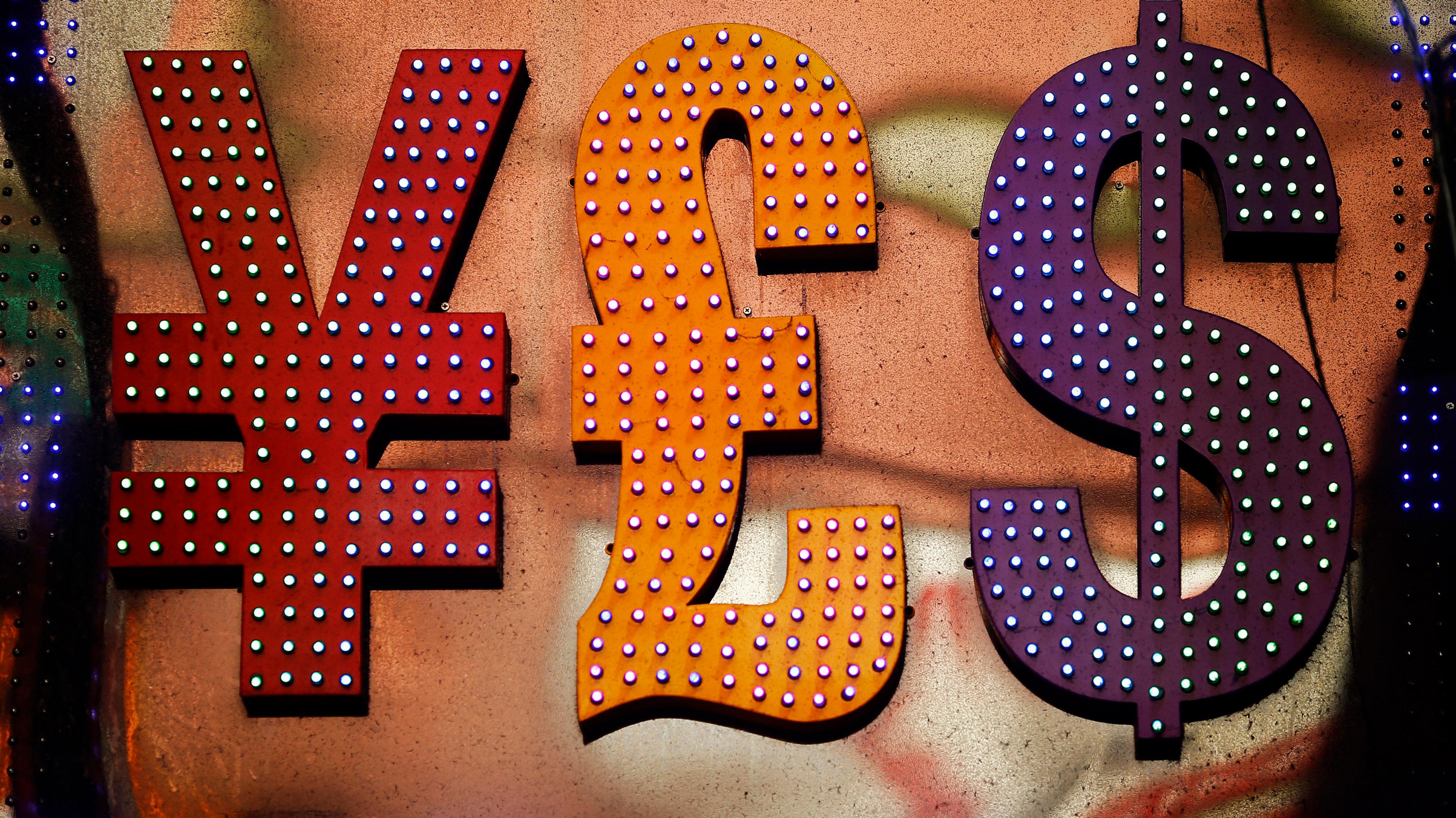 Illuminated currency symbols yen, pound and dollar in red, orange and purple on a textured background.