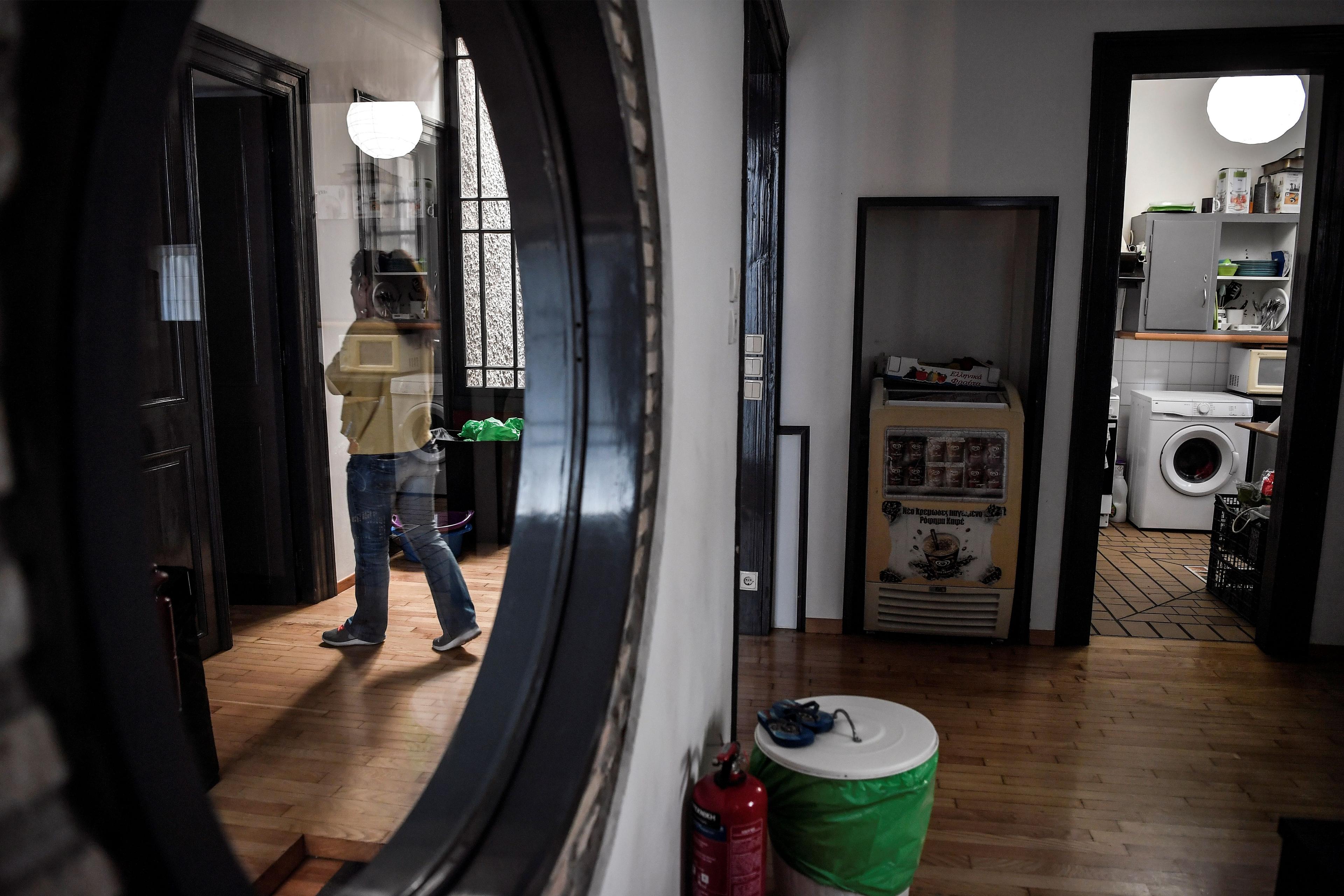 Photo of a hallway with a mirror reflecting a person, a washing machine is visible in a room to the right.