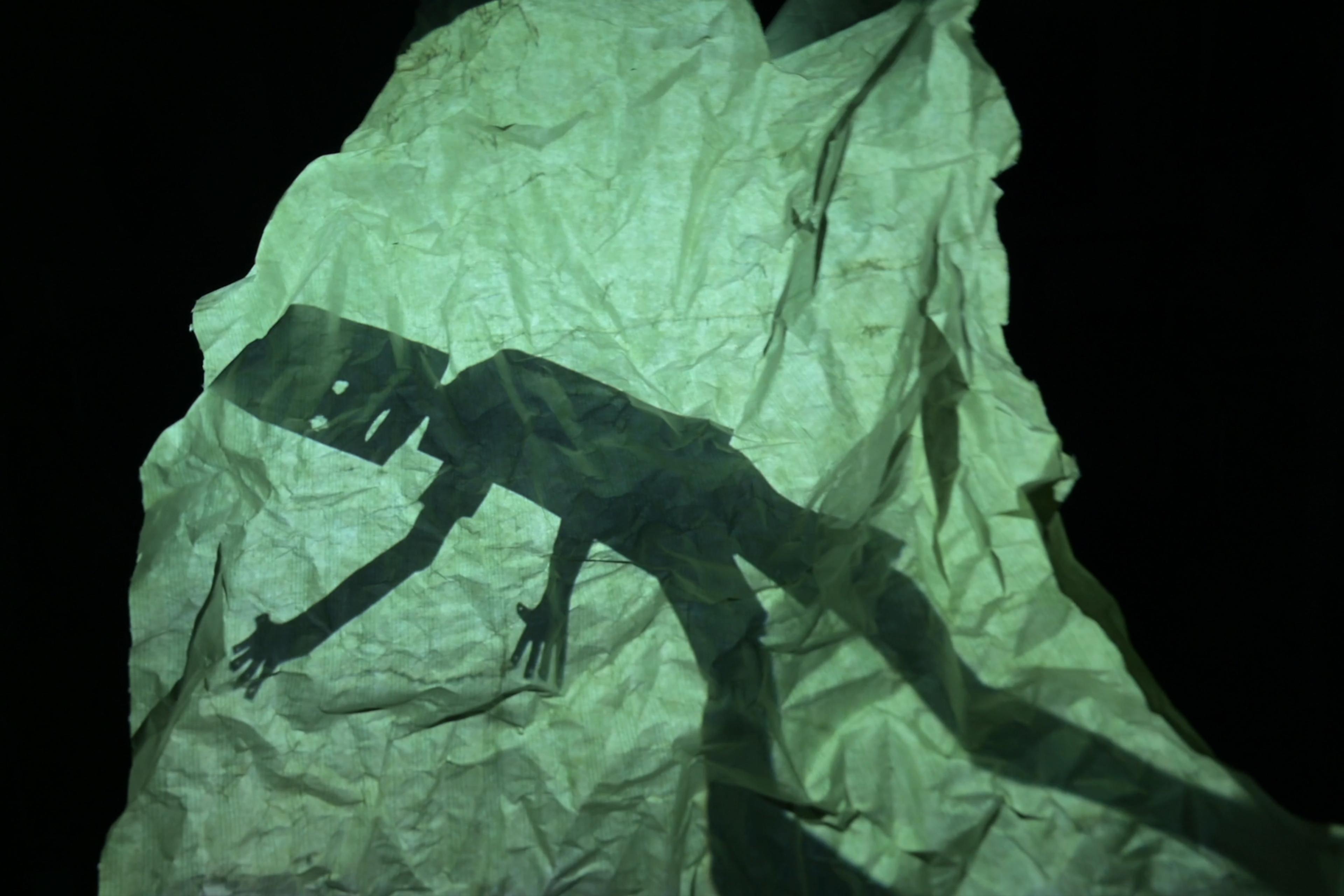 Shadow of a person on crumpled paper in dark setting photo.